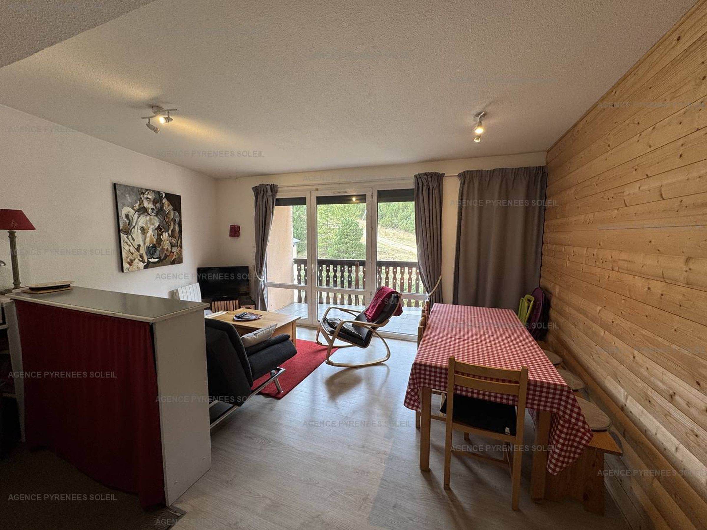 A room with a dining table, a sofa, a TV, and a window with curtains.