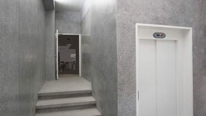 A narrow, concrete stairway leading to a white elevator in a modern building. - Stunningly Beautiful & Modern Apt. Small building (Miraflores)