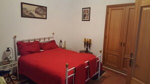 A bedroom with a bed, nightstands, a wooden wardrobe, and two framed pictures on the wall. - Villa with terrace, beaches nearby as well as Évora - museum city.   (Torrao)