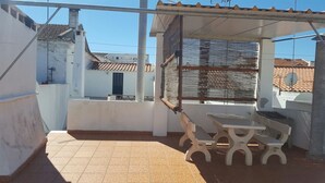 A covered outdoor patio with a table and benches, white walls, and a tiled floor. - Villa with terrace, beaches nearby as well as Évora - museum city.   (Torrao)