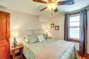 A bedroom with a bed, two bedside tables, a ceiling fan, a window with curtains, and a door. - 'Trout House' in Dtwn Damascus: Near Creeper Trail (Damascus)