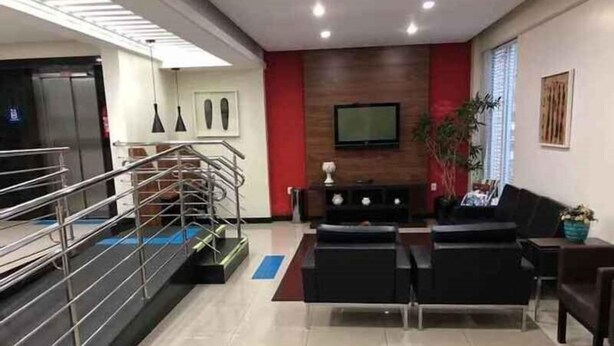 A modern hotel lobby with a reception desk, seating area, and a staircase. - Tri Hotel Centro Chapeco (Chapecó)