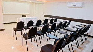 A conference room with rows of chairs, a projector screen, and a table with a white tablecloth. - Tri Hotel Centro Chapeco (Chapecó)