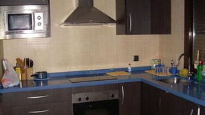 Een keuken met donkere kastjes, een magnetron, een fornuis en een spoelbak.