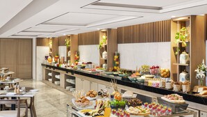 Een buffet met diverse gerechten en een zithoek met tafels en stoelen.