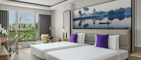 A hotel room with two beds, a desk, a chair, a large window with a view of greenery, and a painting on the wall.