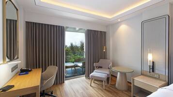 A modern hotel room with a wooden desk, a comfortable armchair, a small round table, and a bed.