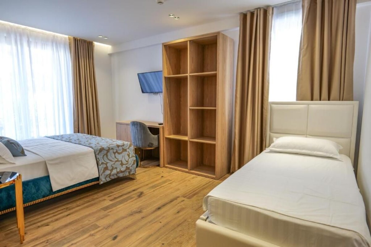 A hotel room with a bed, a desk, a wardrobe, and a television.