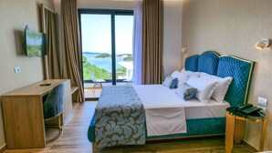Ein Hotelzimmer mit Bett, Fernseher, Schreibtisch und Meerblick.