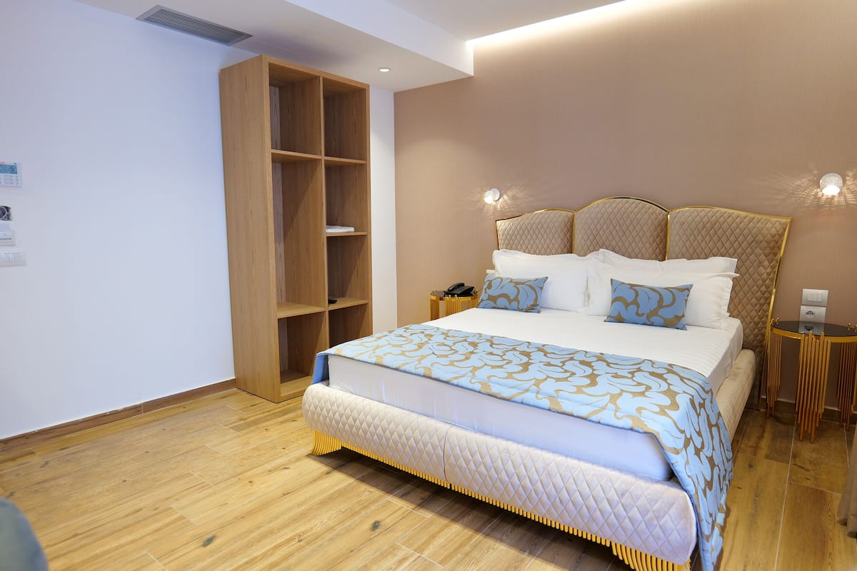 Un dormitorio moderno con una cama grande, armario de madera, mesitas de noche e iluminación en la pared.