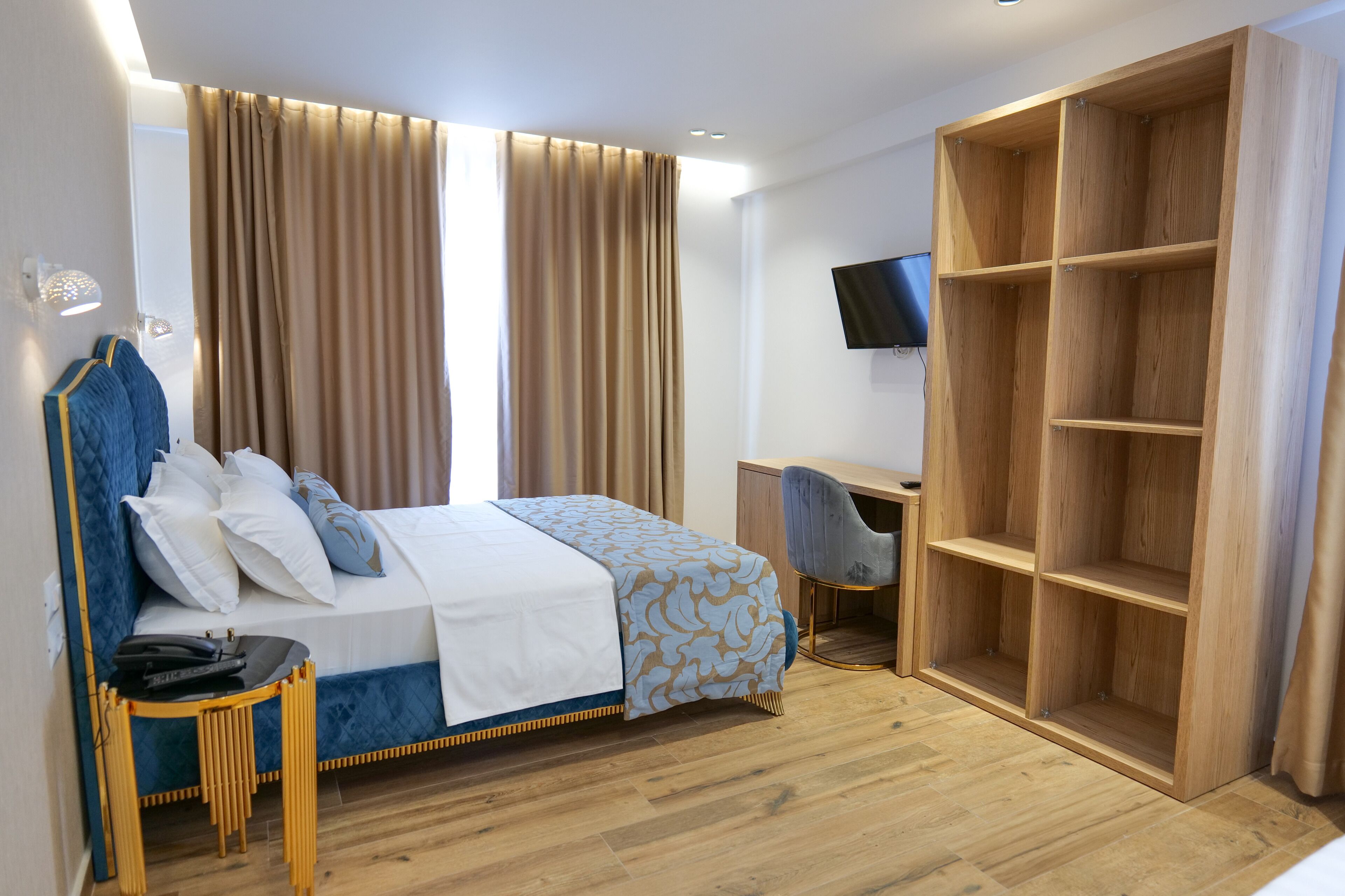 A hotel room with a bed, a desk, and a wardrobe.
