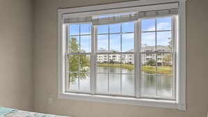 Ein Zimmer mit großem Fenster mit Blick auf ein Gewässer und einen Gebäudekomplex.