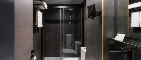 A modern bathroom with a glass-enclosed shower, a toilet, and a sink.