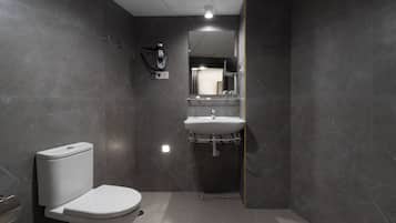 Une salle de bain moderne équipée de toilettes, d’un lavabo et d’un sèche-cheveux.
