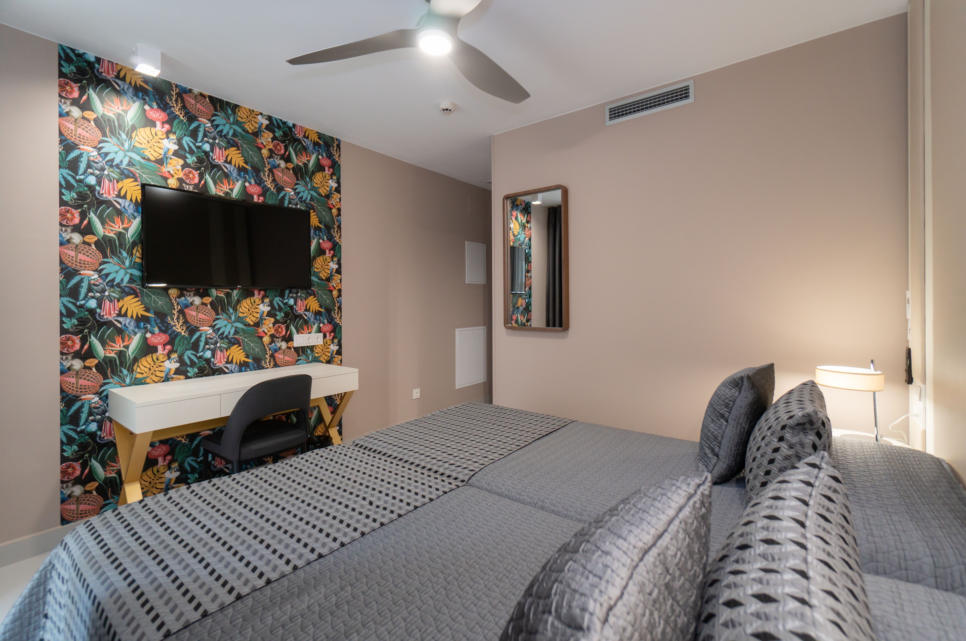 Une chambre à coucher comprenant un lit, un bureau, une chaise, une télévision, un miroir et une lampe.