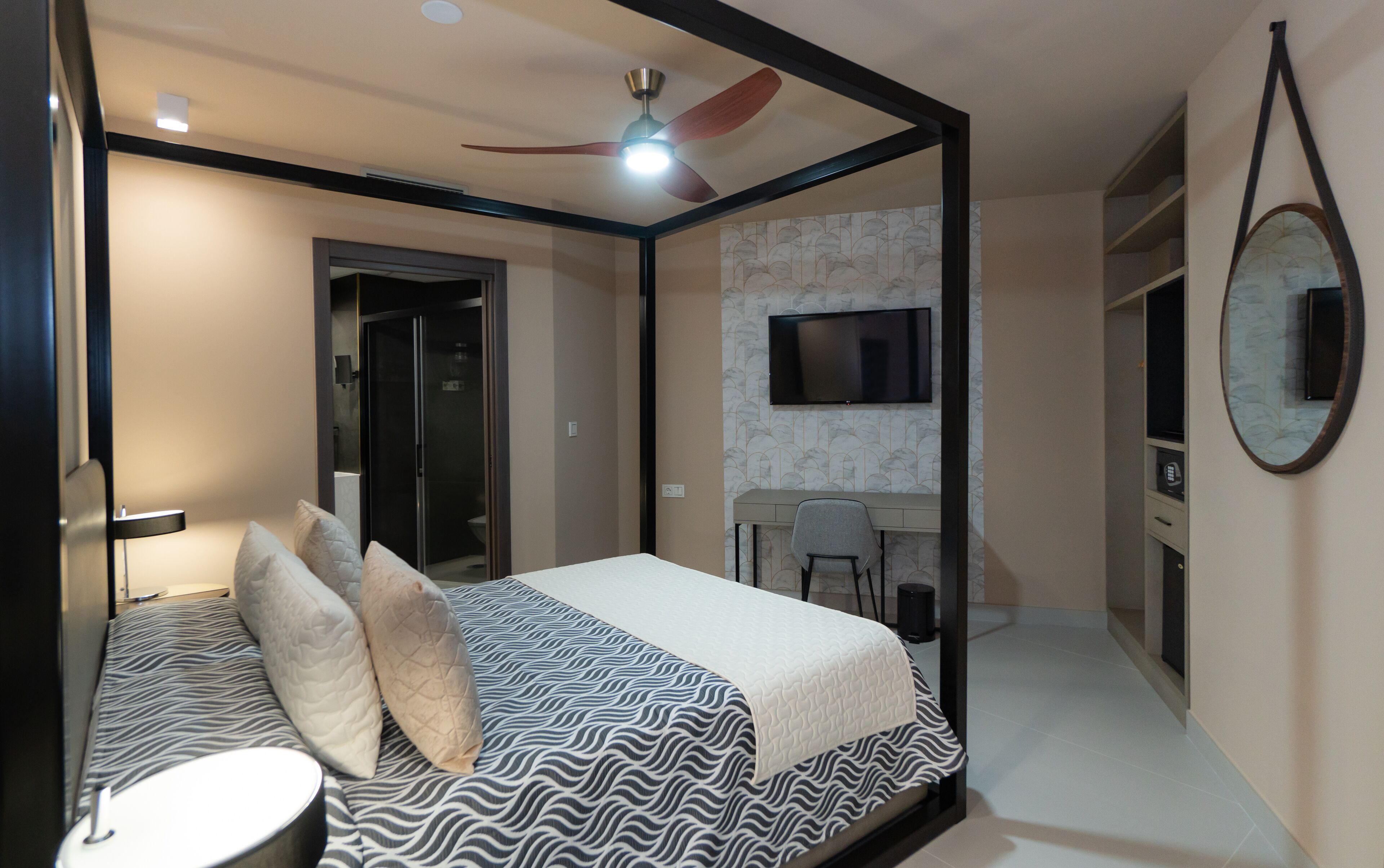 A bedroom with a bed, a desk, a chair, a television, and a bathroom.