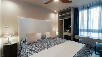 Una habitación de hotel moderna con una cama grande, un escritorio y un armario.