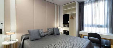 Habitación de hotel moderna con una cama grande, un escritorio y un armario.