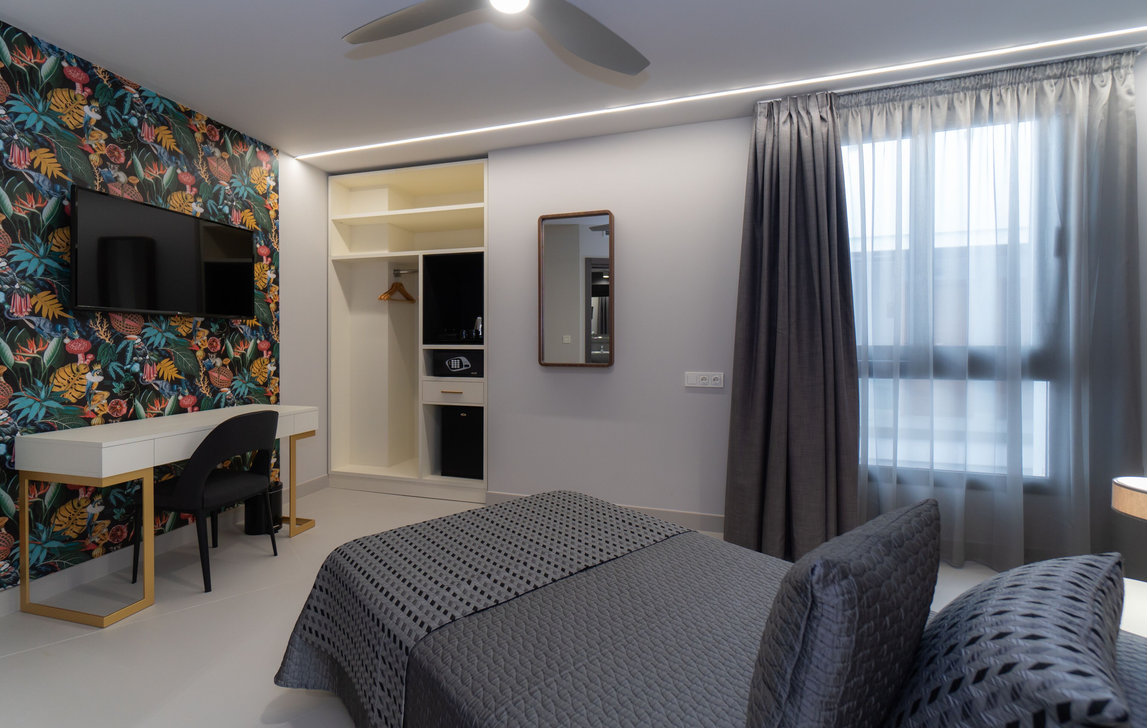 Een moderne slaapkamer met een bed, een bureau en een kledingkast.