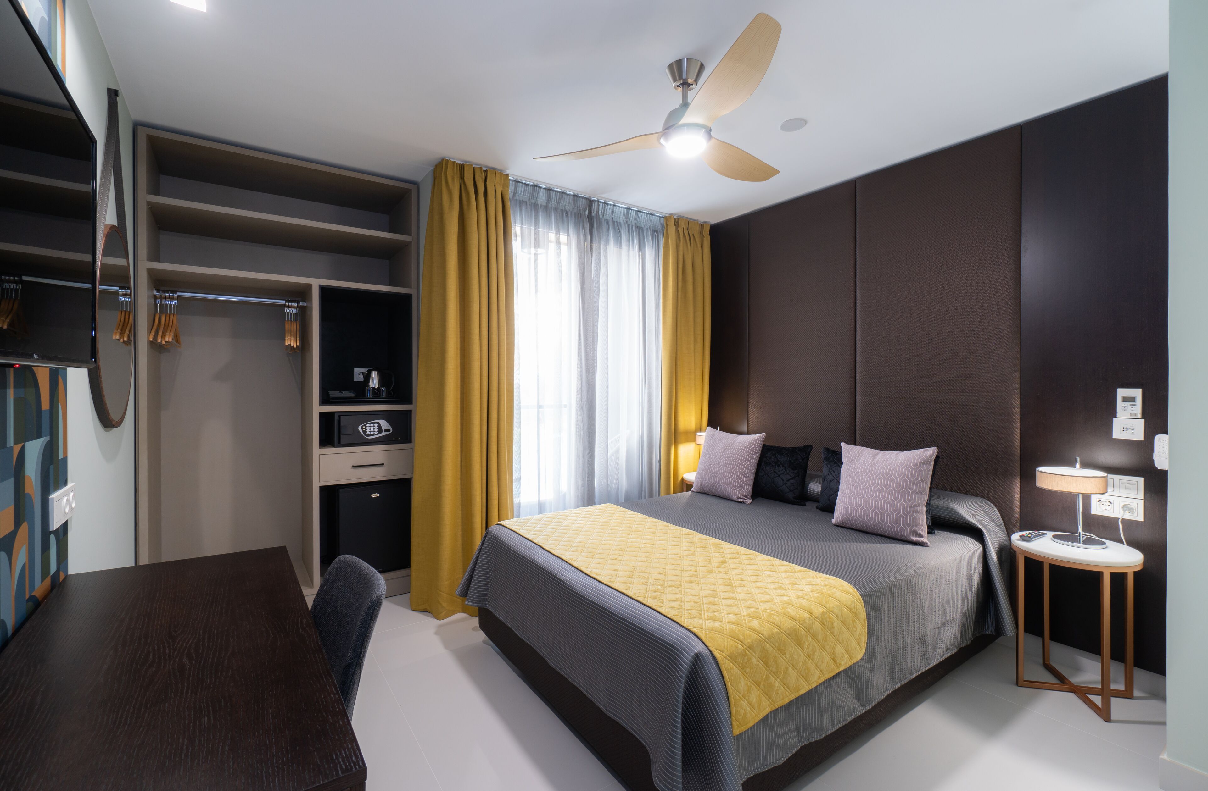 Une chambre d’hôtel moderne équipée d’un lit, d’une table de chevet et d’un ventilateur de plafond.