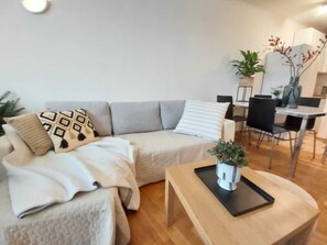 Relax in this stylish living area with a sofa, dining table, and potted plant.