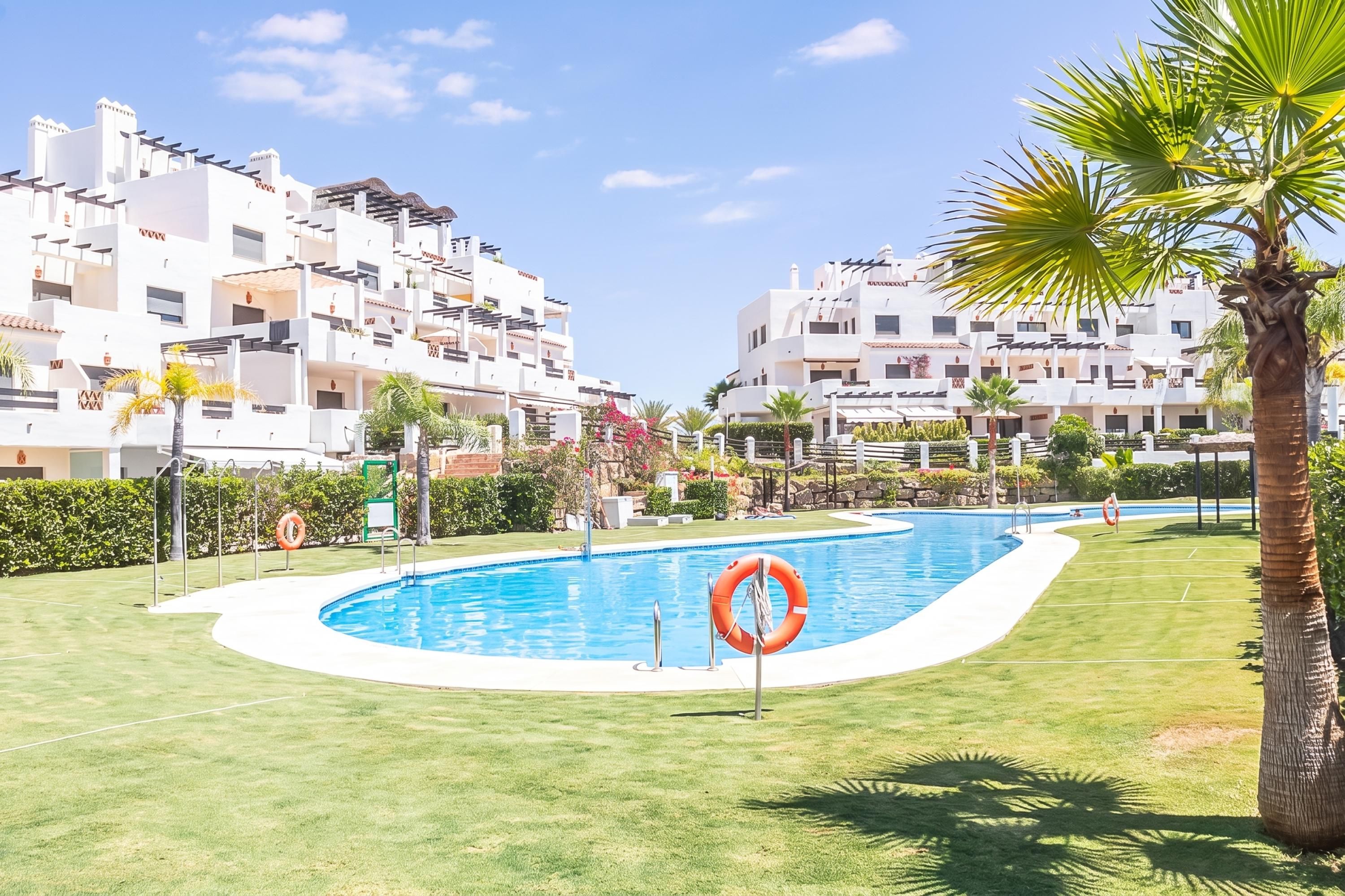 A swimming pool surrounded by a well-maintained lawn, with a palm tree and a lifebuoy visible.