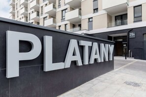 A modern building with a prominent 'PLATANY' sign, a balcony, and a door marked '29A'.