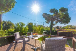 An outdoor deck with wicker furniture, a table with a bottle and glasses, and a bowl of fruit. - Villa Revita Kourouta Beach (Ilida)