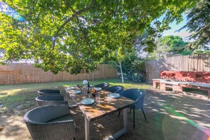 An outdoor dining area with a wooden table set for four, surrounded by wicker chairs, under a large tree. - Villa Revita Kourouta Beach (Ilida)