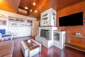A modern living room with a fireplace, a flat-screen TV, a bookshelf, and a coffee table. - Villa Revita Kourouta Beach (Ilida)