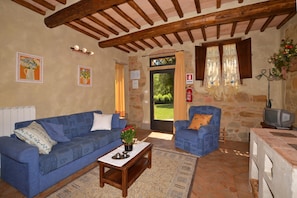 A cozy living room with a blue sofa, a small table with a plant, and a stone fireplace.