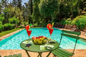A poolside setting with a table, chairs, and a bench.