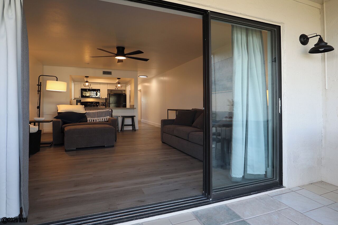 A modern living room with a sofa, a dining table, and a kitchen in the background.