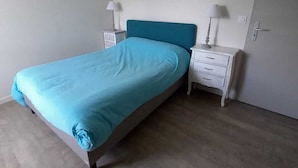 A bedroom with a bed, two bedside tables, a hanging light fixture, and a door. - Comfortable house in Portnavalo by the sea (Arzon)