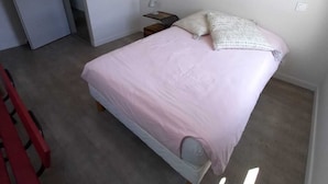 A bedroom with a bed, a nightstand, a lamp, and a red chair. - Comfortable house in Portnavalo by the sea (Arzon)