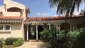 A two-story building with a covered patio area, a satellite dish, and a palm tree. - House (Saly)