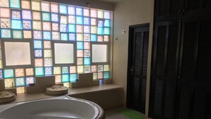 A bathroom with a large bathtub, a window with colorful stained glass, and a door with louvered shutters. - House (Saly)