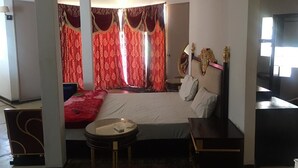 A bedroom with a large bed, a bedside table, a round table, and a TV. - House (Saly)