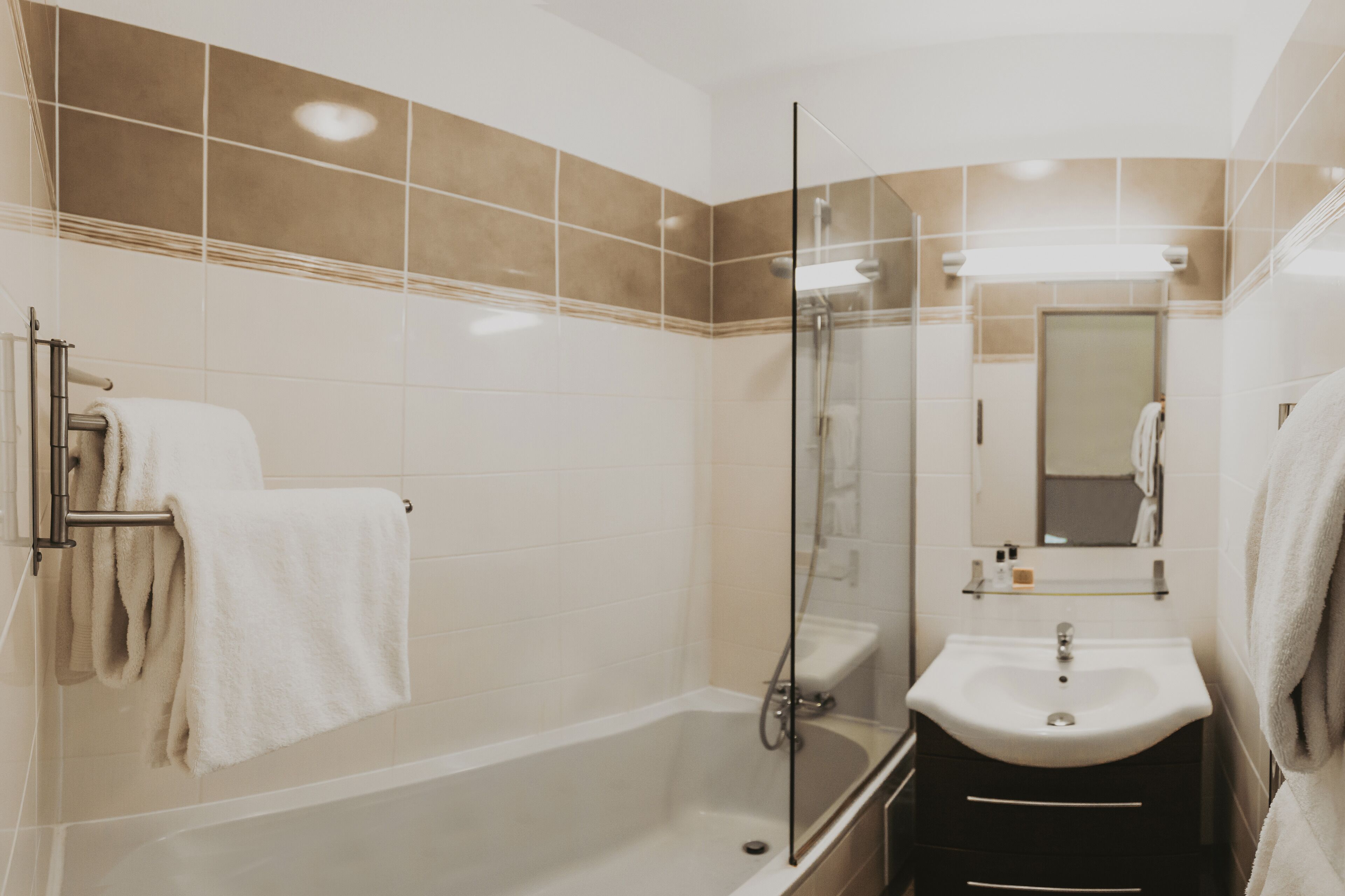 Ein modernes Badezimmer mit einer gläsernen Dusche, einem weißen Waschbecken und einem Spiegel darüber.