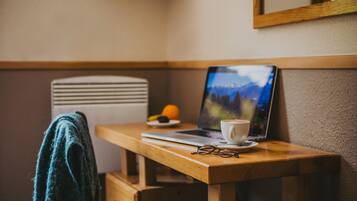 Een houten bureau met een laptop, een kop koffie en een paar brillen.