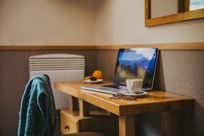 A wooden desk with a laptop, a cup of coffee, and a pair of glasses. - Hôtel Les Grangettes (Les Allues)