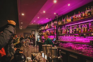 Un espace bar avec des étagères remplies de bouteilles d’alcool et de verres.