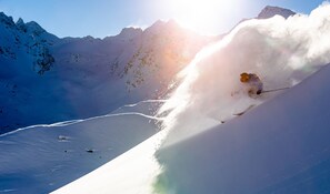 A skier navigating a steep, snow-covered slope with a clear sky and distant mountains. - Hôtel Les Grangettes (Les Allues)