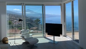 Una sala de estar moderna con un televisor grande, un sillón blanco elegante y una lámpara de pie.