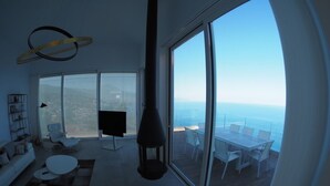 Una sala de estar moderna con un amplio ventanal corredero que da a un espacio exterior para comer.