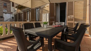 Eine Terrassengaststätte mit Tisch und Stühlen, einem Blumentopf und einer Tischdekoration mit Weingläsern.