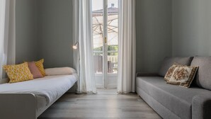 Ein Zimmer mit einem Bett, einem Sofa und Blick auf einen Innenhof durch eine Glastür.