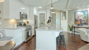 Una cocina moderna con armarios blancos, electrodomésticos de acero inoxidable y una isla central.