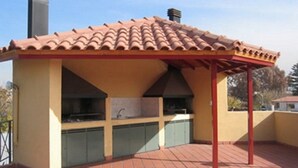 Un espace cuisine extérieur doté d’un toit en tuiles, de meubles encastrés et d’une cheminée.
