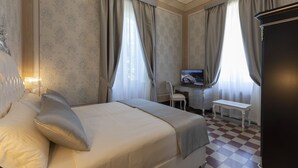 Une chambre d’hôtel équipée d’un lit, d’un bureau, d’une chaise et d’un téléviseur.